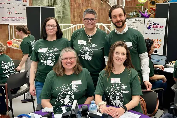 Several people wearing green shirts seated at a table.