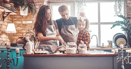 In a bright kitchen, a man and woman collaborate on meal preparation, chopping vegetables and mixing ingredients.
