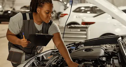 A woman inspects the engine of a car, focused on ensuring its proper functioning.