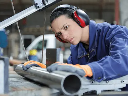 A woman wearing ear protection, focused on her task in a noisy environment, ensuring her hearing safety.
