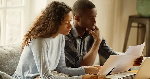 A couple reviewing documents together on a laptop, focused on the screen and discussing the content.
