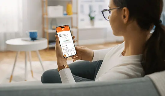 person sitting on couch looking at a smartphone with the Direct Energy app. 