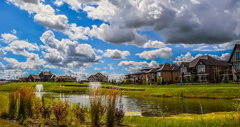 Scenic view of a tranquil lake surrounded by charming houses under a clear blue sky.