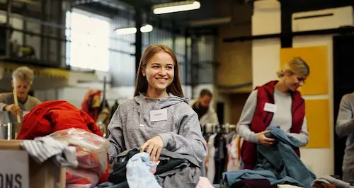 A woman smiles while holding a bag filled with clothes, showcasing her joy and excitement.