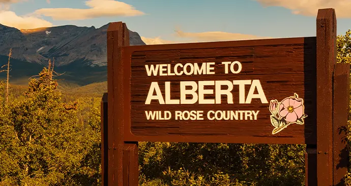 welcome to Alberta sign with mountains in the background