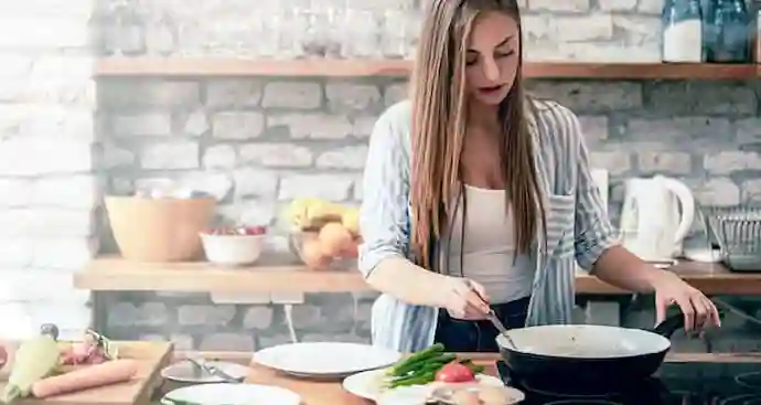 A young woman cooking a healthy meal on stove top