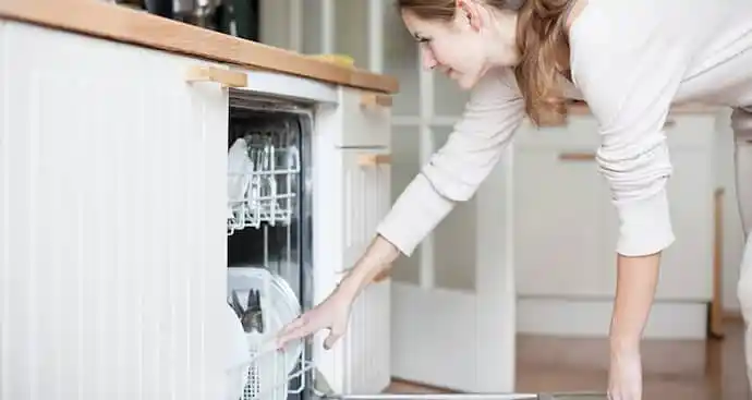 Young woman putting dishes in the dishwasher