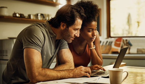 Couple looking at laptop with papers on counter