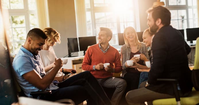 Coworkers gathered around a table, sharing coffee and conversation during their break, promoting teamwork and relaxation.