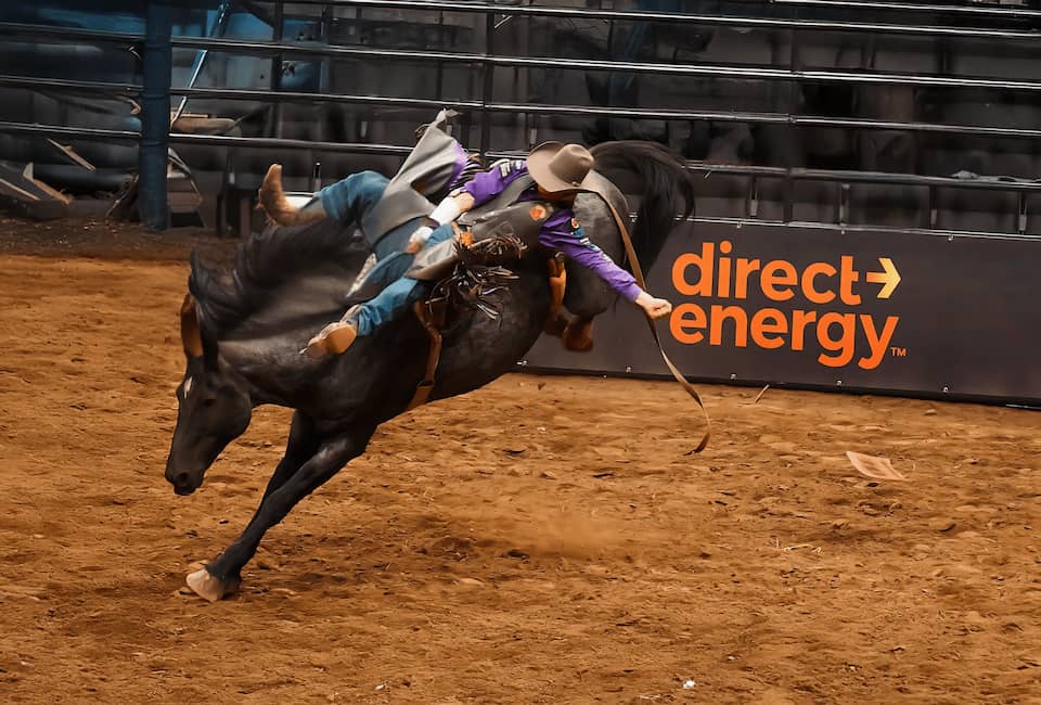 Cowboy riding horse in rodeo with the Direct Energy logo behind