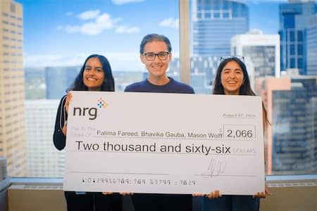 Three individuals proudly display a check for $2,006, celebrating their achievement together.