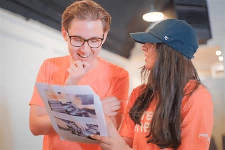 Two individuals in orange Direct Energy shirts examining a document together.
