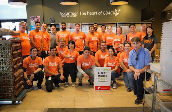 A woman in a clothing store holds a tablet, engaged in selecting and reviewing clothing items on display.