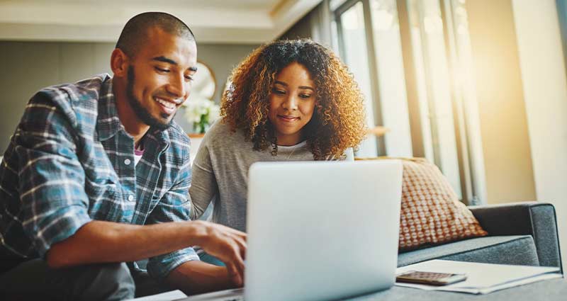 A man and woman focus on a laptop screen, engaged in discussion and sharing ideas in a professional environment.