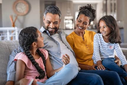 A family gathered on a couch, sharing laughter and warmth in a comfortable living room setting.