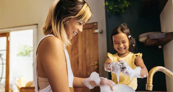 Mother and daughter washing dishes smiling and laughing