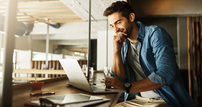 Young man sitting at desk smiling at laptop
