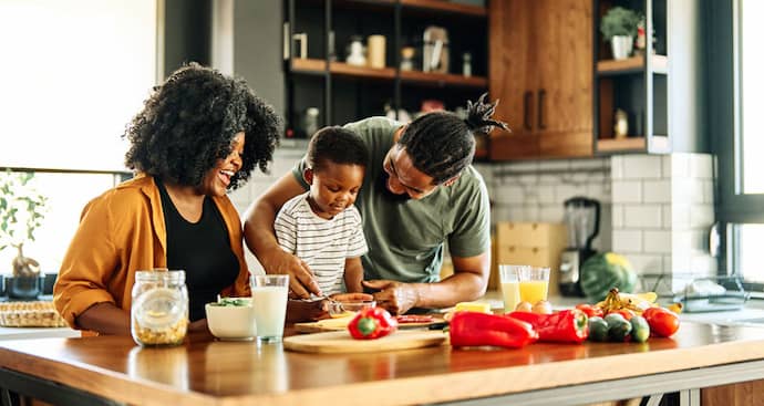 A family collaborates in the kitchen, chopping vegetables and mixing ingredients for a meal preparation.