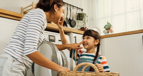 Mother and daughter doing laundry smiling