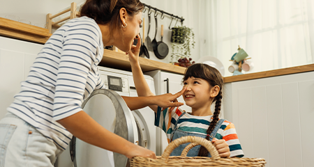 Mother and daughter doing laundry smiling