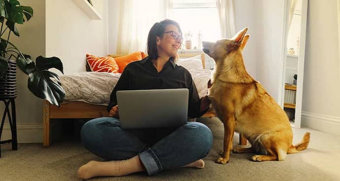 Woman on laptop with dog next to her