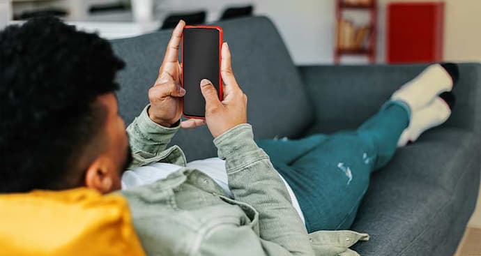 Man laying on couch using phone