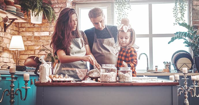 In a bright kitchen, a man and woman collaborate on meal preparation, chopping vegetables and mixing ingredients.
