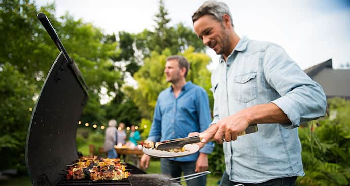 Man barbecuing in the backyard, serving up a plate