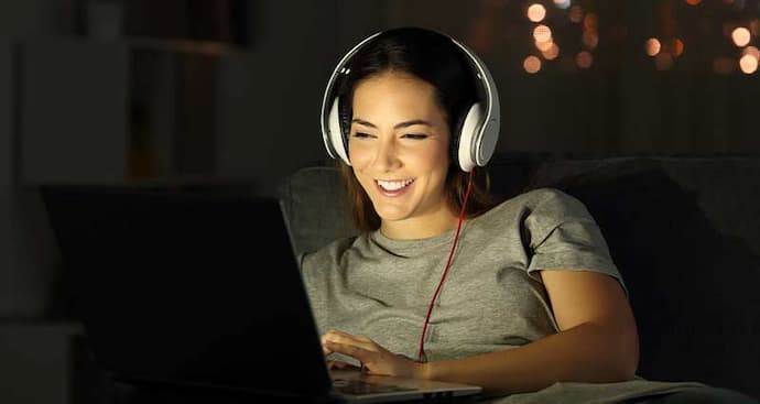 Woman on laptop with headphones smiling