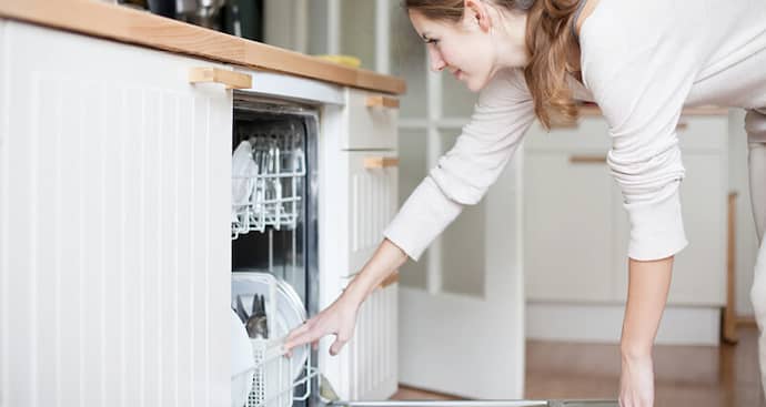 Young woman putting dishes in the dishwasher
