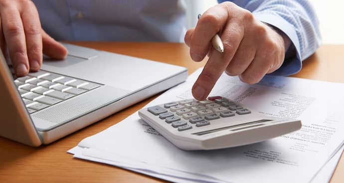 Man typing on calculator and laptop