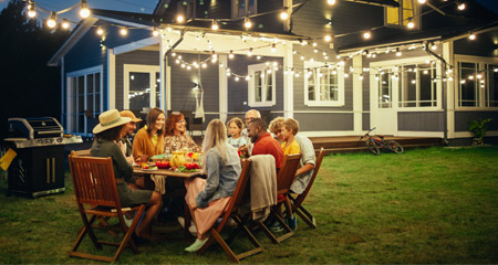 Family and friends enjoying an evening eating dinner in the backyard