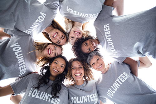 Happy multi-ethnic volunteers forming a huddle.