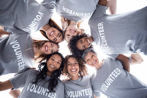 Happy multi-ethnic volunteers forming a huddle.