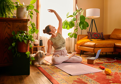 A woman sitting cross-legged on a yoga mat, practicing mindfulness in a serene indoor environment.