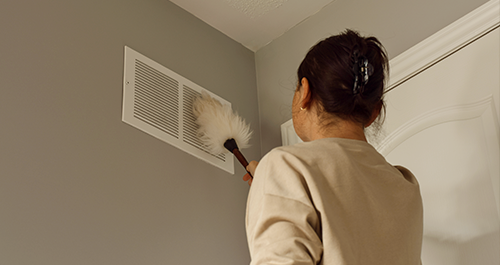 Woman cleaning air vent with duster