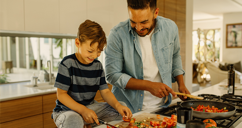 Father and son chopping and cooking red peppers 