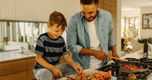Father and son chopping and cooking red peppers 