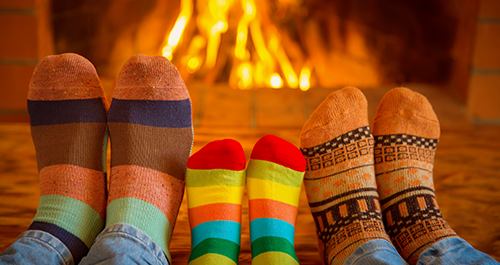Three people with colourful socks in front of fireplace