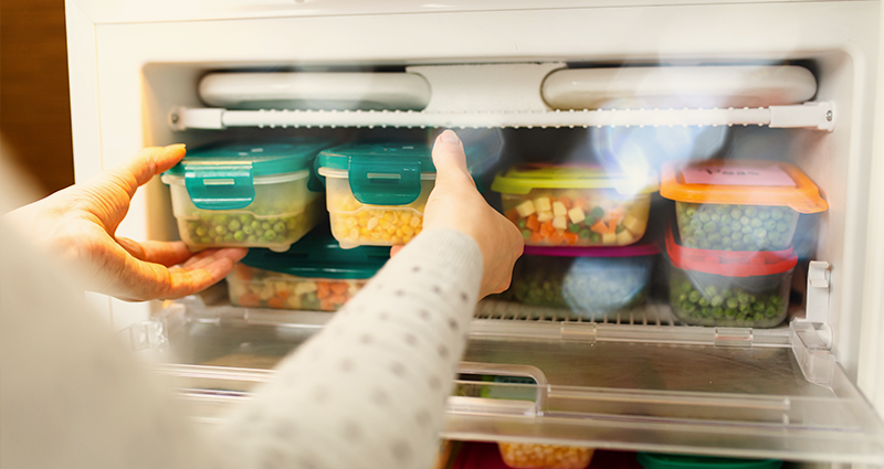 Woman placing vegetables into freezer
