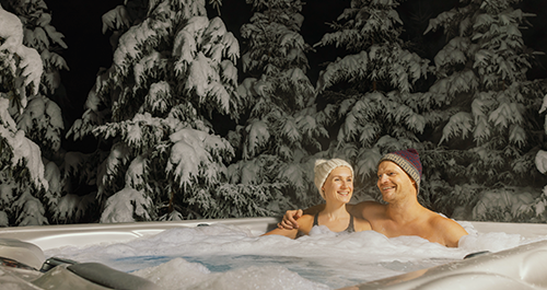 Couple with toques on sitting in hot tub in the winter