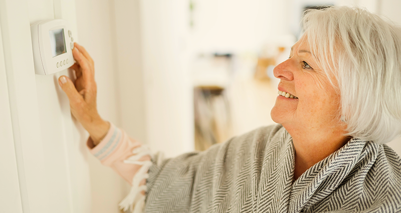 Older woman adjusting thermostat