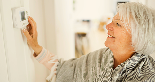 Older woman adjusting thermostat