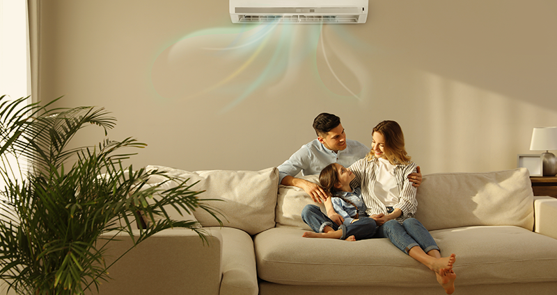 Family of three sitting under portable air conditioning unit