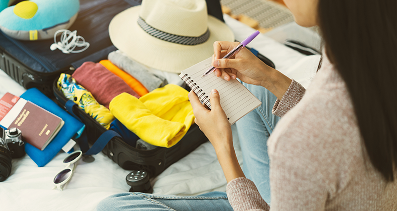 Woman packing for vacation with checklist in hand