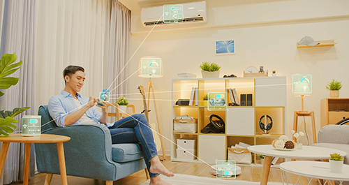 Guy sitting in a chair in his living room on mobile phone showcasing all of the devices he can access 