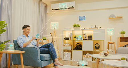 Guy sitting in a chair in his living room on mobile phone showcasing all of the devices he can access 
