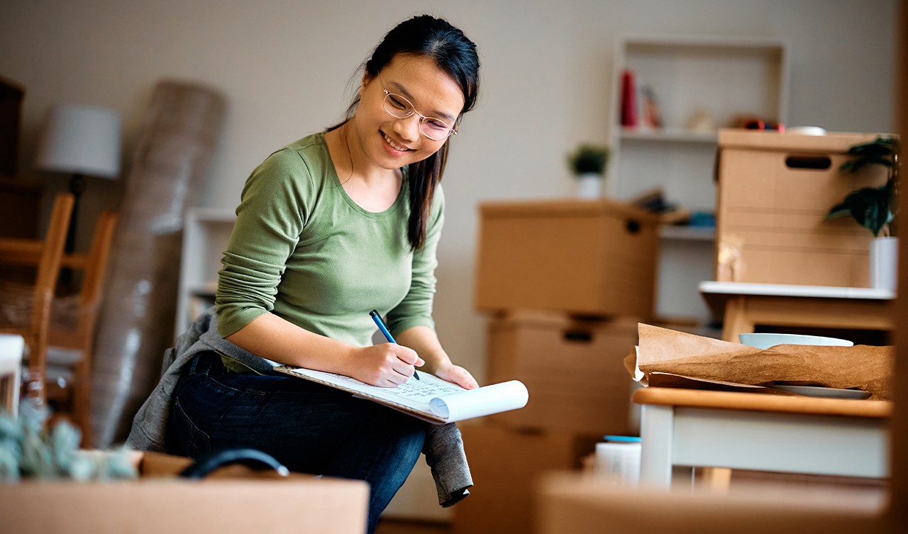 Woman packing boxes with a check list getting ready to move