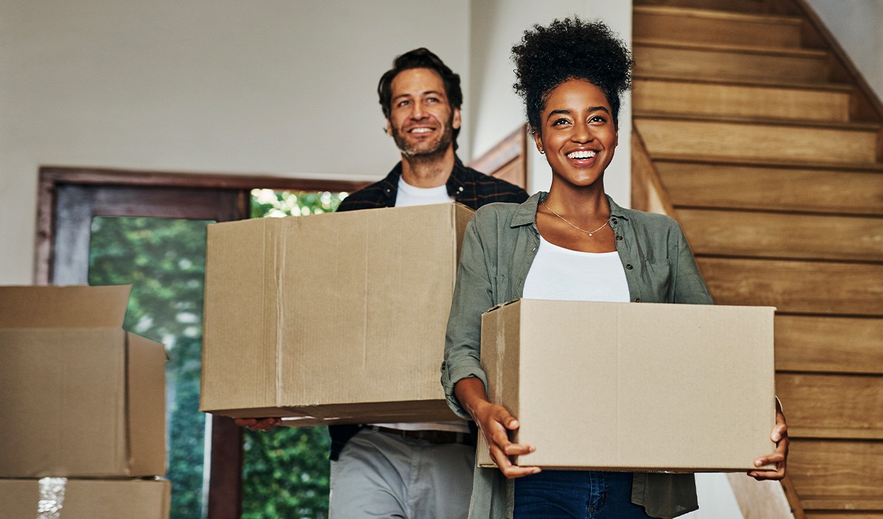 Couple moving into their new home carrying boxes