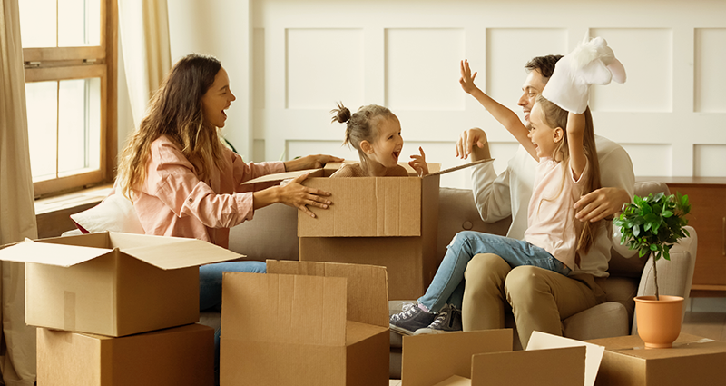 Family laughing with daughter popping out of moving box